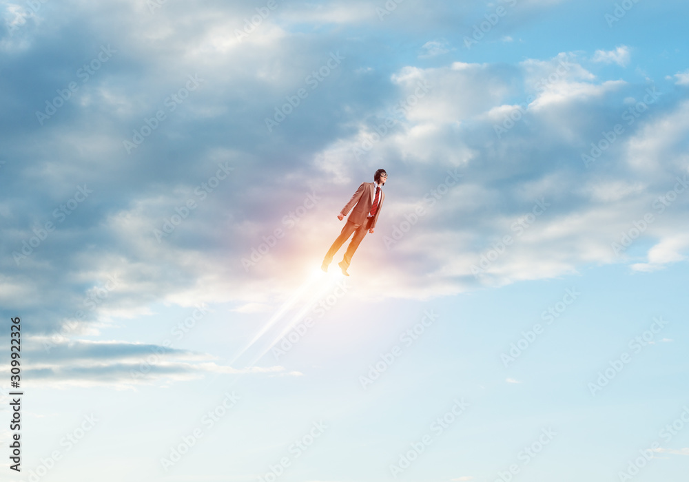 Businessman in suit and aviator hat flying in sky