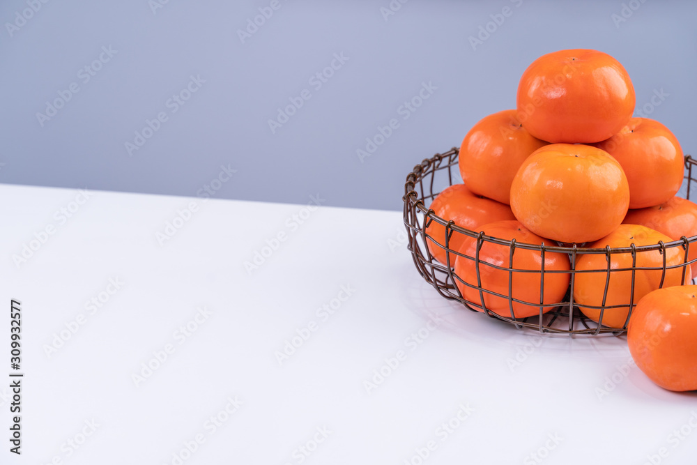 Fresh beautiful sliced sweet persimmon kaki isolated on white kitchen table with gray blue backgroun