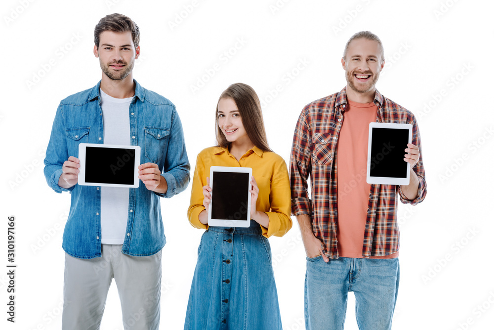 smiling three young friends holding digital tablets with blank screens isolated on white