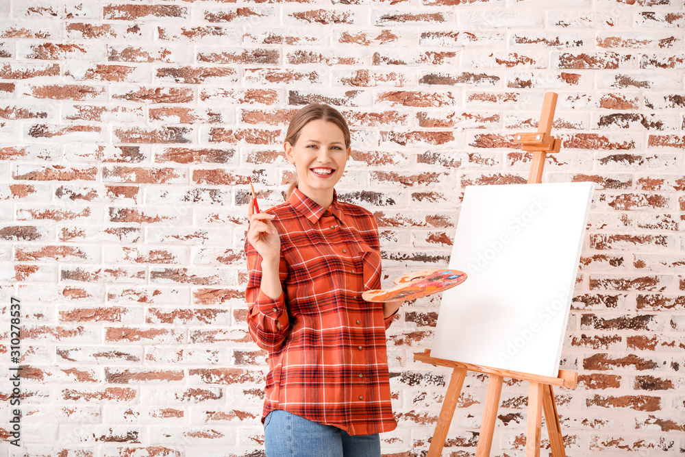 Young female artist against brick wall