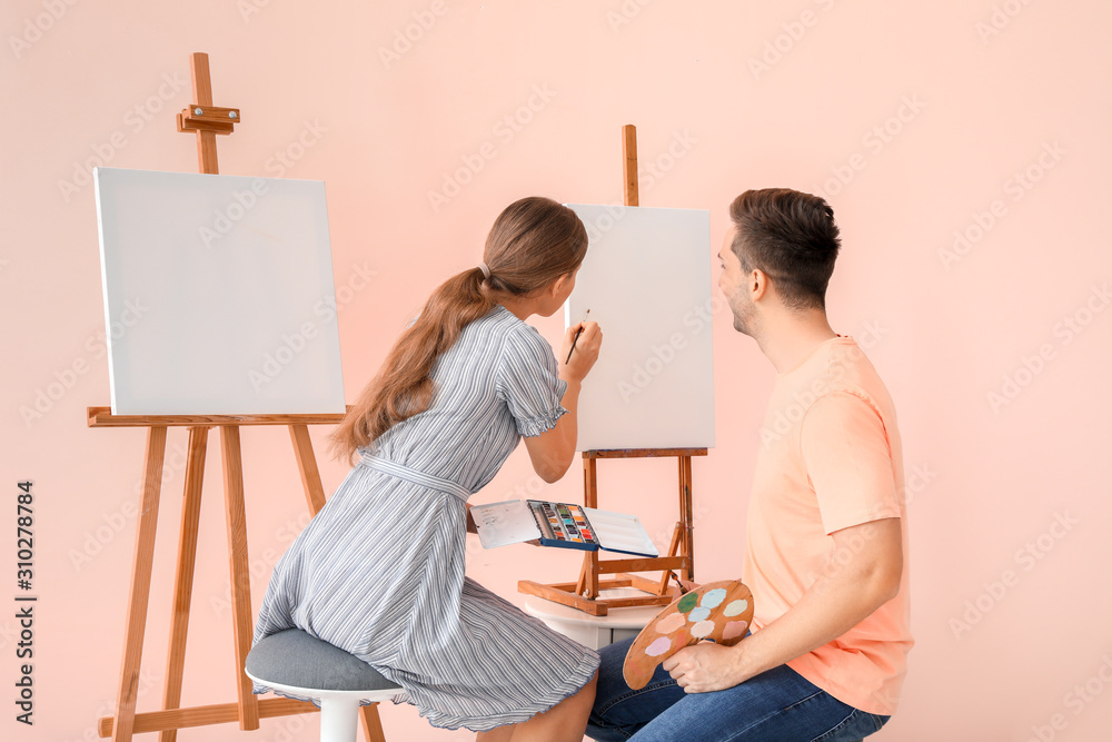 Couple of young artists on color background