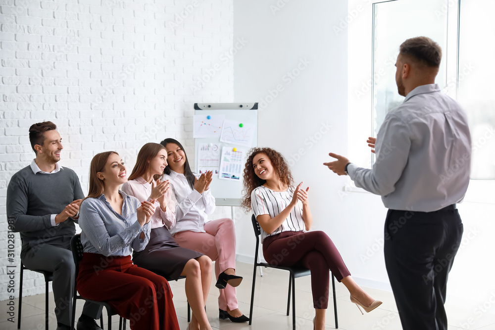 Colleagues listening to speaker at business meeting in office