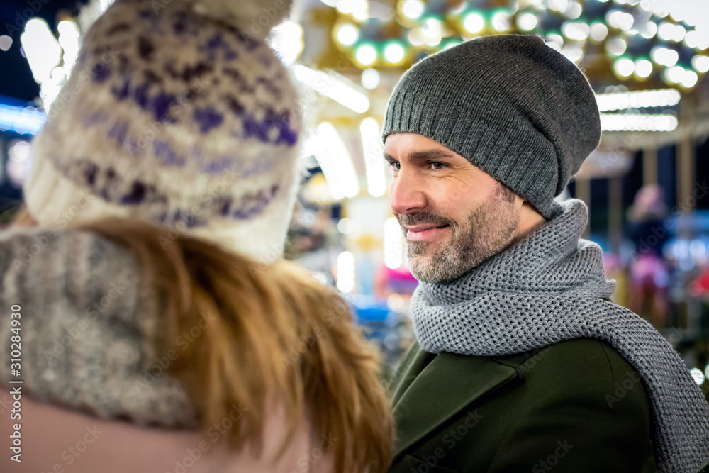 Sweet couple spend time together at the Christmas market in the evening