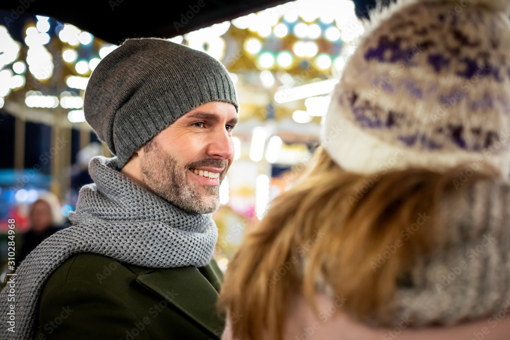 Sweet couple spend time together at the Christmas market in the evening