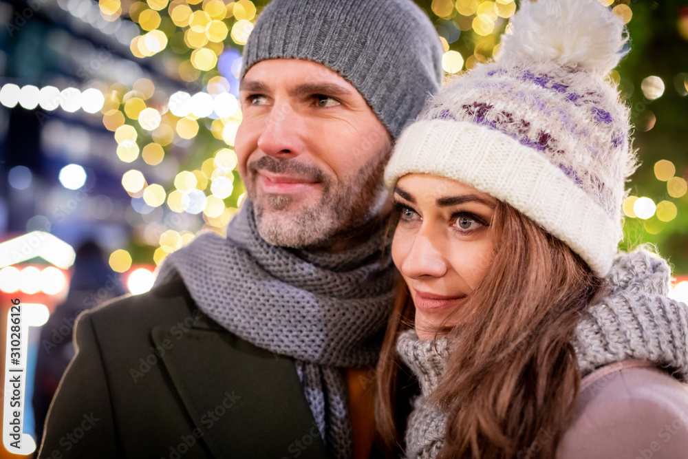 Portrait of a loving couple among Christmas street decorations during winter holidays