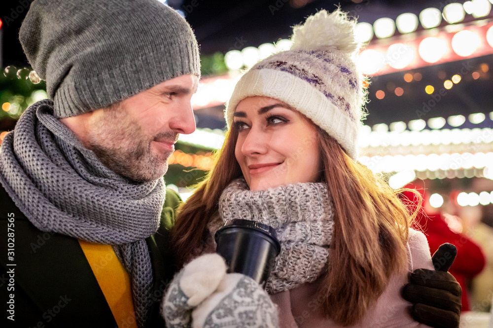 Loving couple on the background of winter holidays decorations during an evening walk around Christm