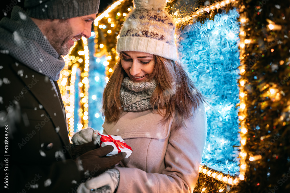 Giving a Christmas gift among decorations while walking around the market