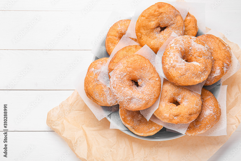 Plate with sweet tasty donuts on white wooden background