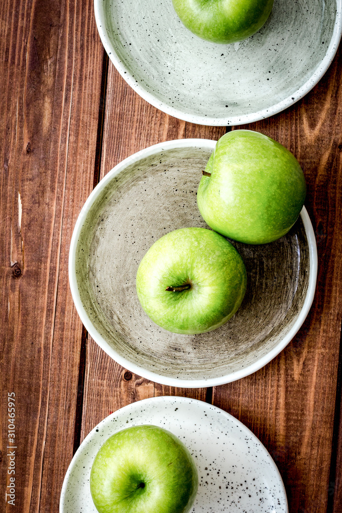 Healthy green food with apples on plates wooden background top view