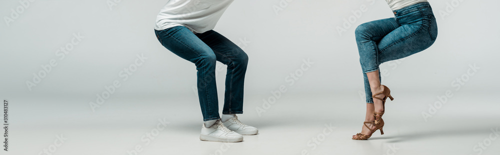 panoramic shot of dancers in denim jeans dancing bachata on grey background