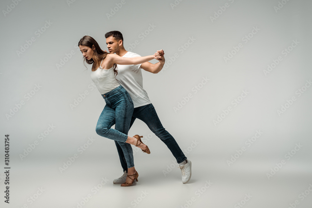 dancers in denim jeans dancing bachata on grey background