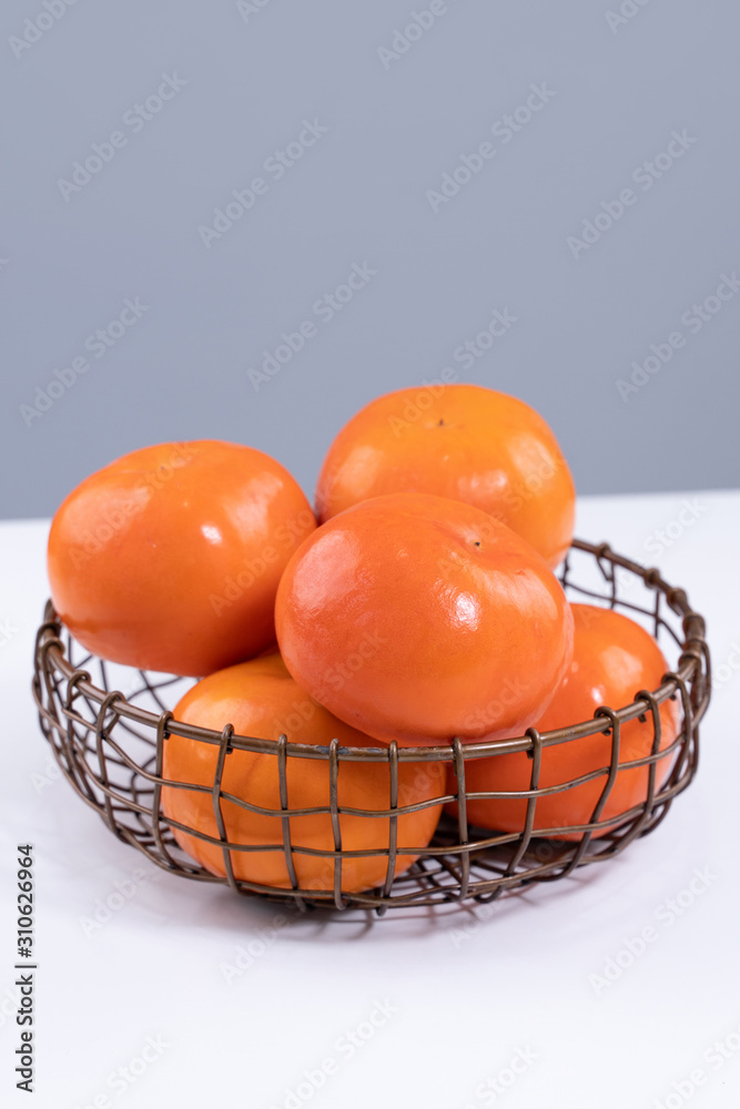 Fresh beautiful sliced sweet persimmon kaki isolated on white kitchen table with gray blue backgroun