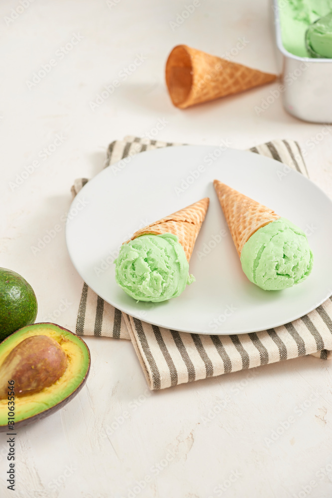 Green avocado ice cream scoops in wafle cones on white background. Copy space