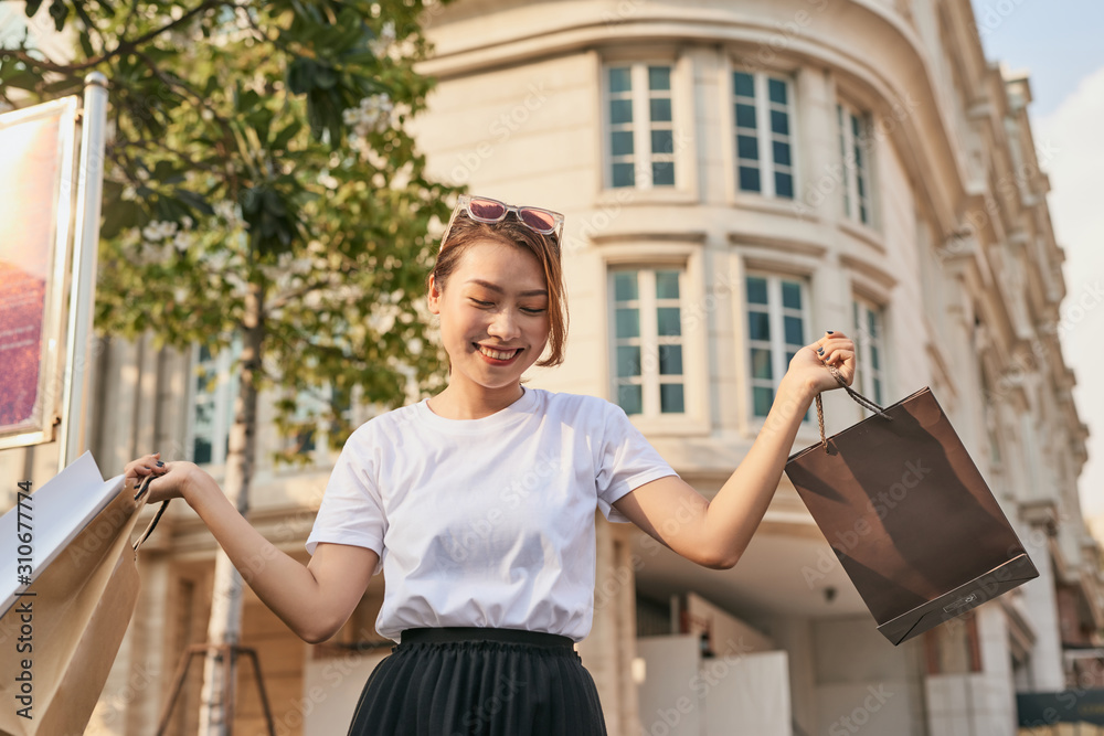 快乐的年轻女人在商场大减价购物后散步