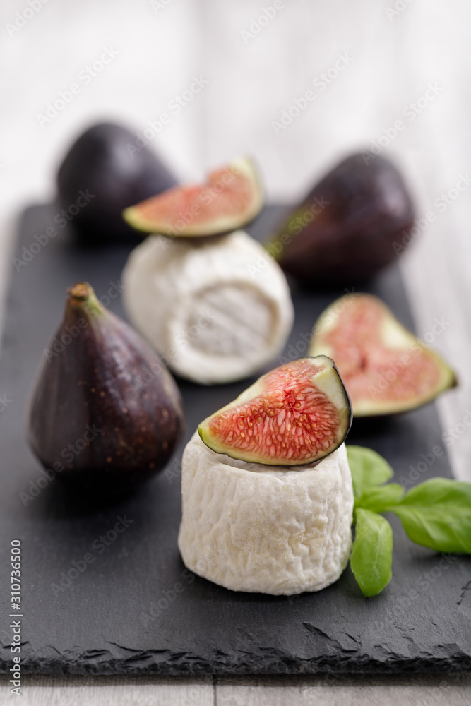 Fresh sweet figs and  goat cheese on dark stone board - healthy diet. Selective focus with copy spac