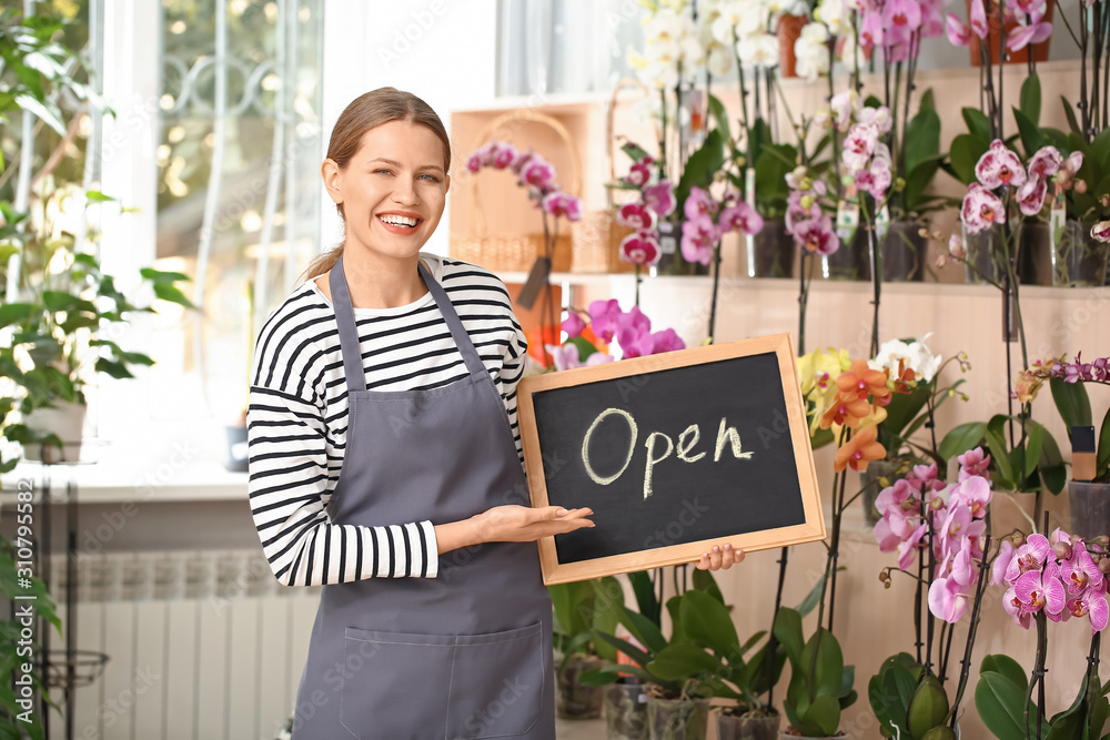 Florist holding chalkboard with text OPEN in shop