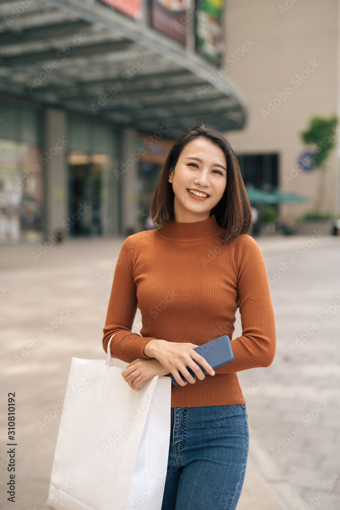 户外购物中心快乐的亚洲年轻女子拿着购物袋的肖像