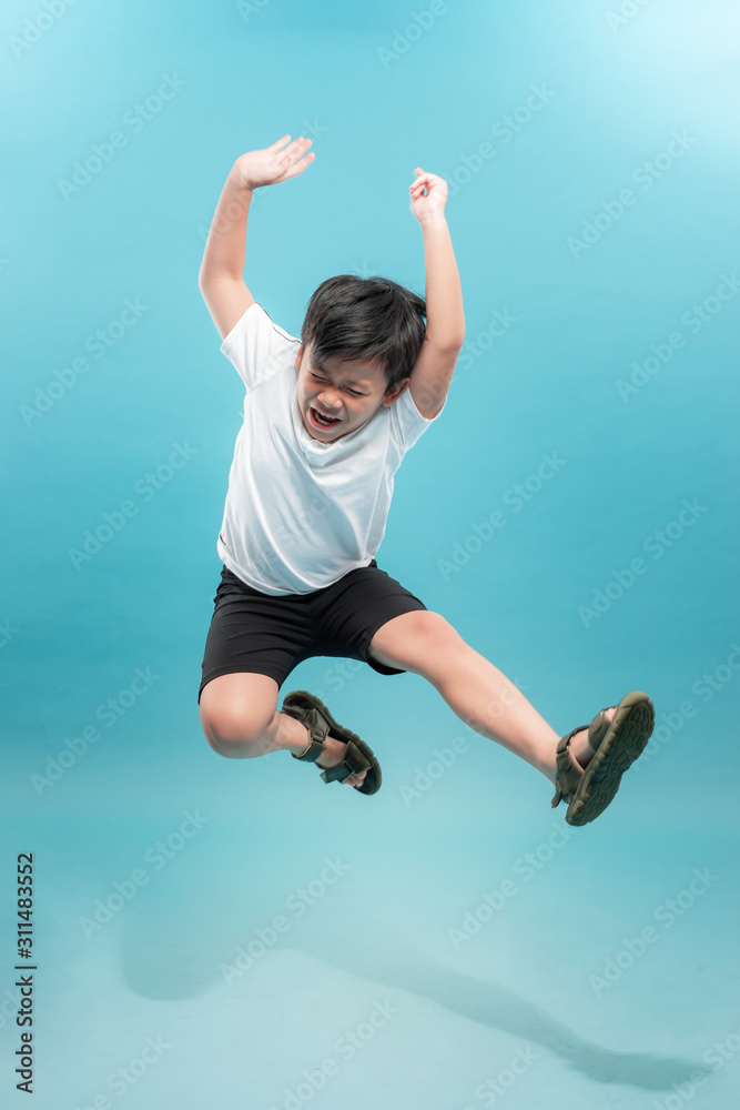 A full length portrait of a handsome child boy jumping in the studio over light background. Kids, fa