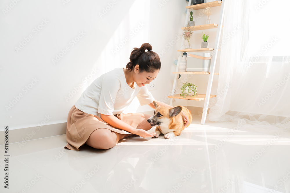 快乐的亚洲女人和她的柯基犬玩耍