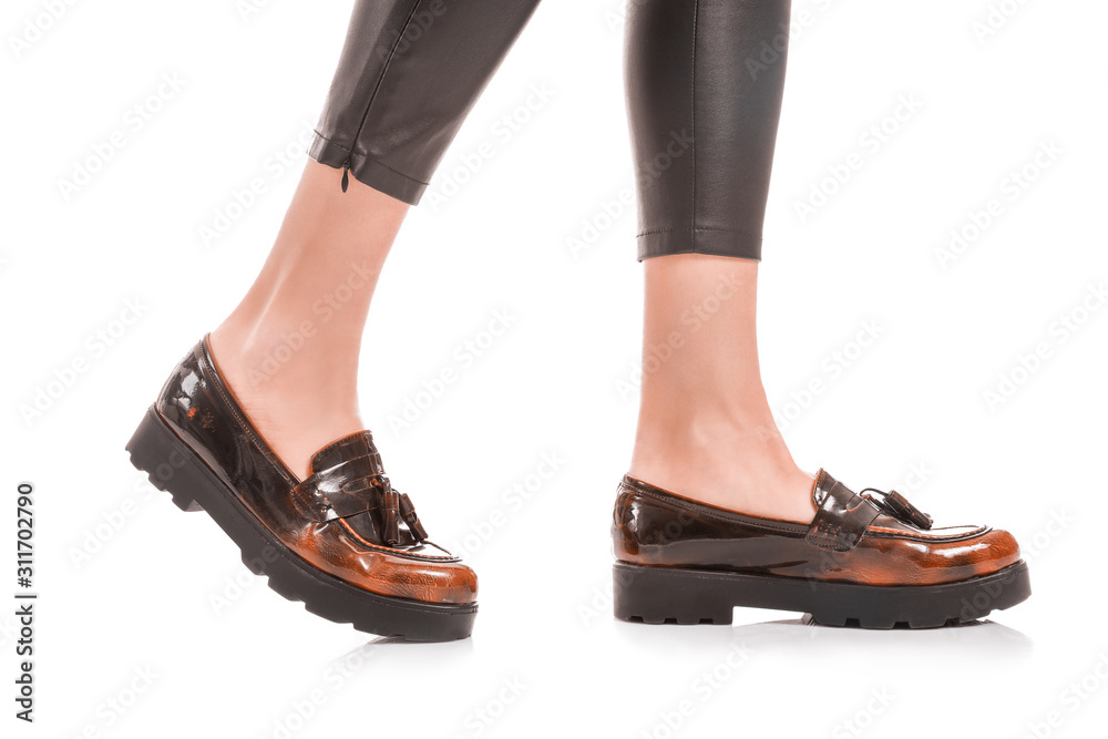 Legs of stylish young woman in shoes and leather pants on white background