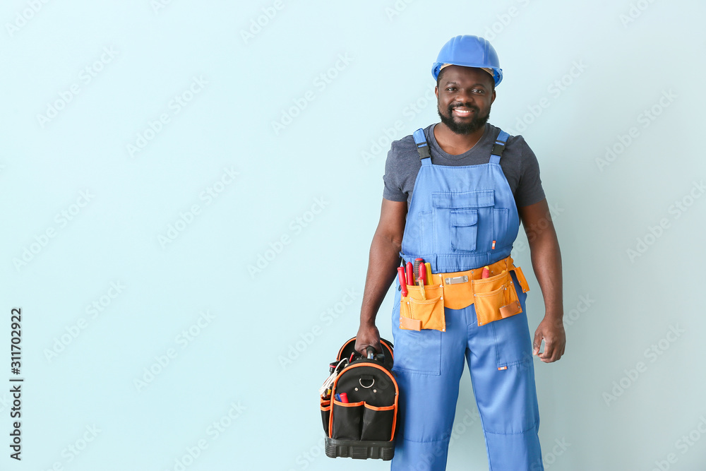 African-American electrician on color background