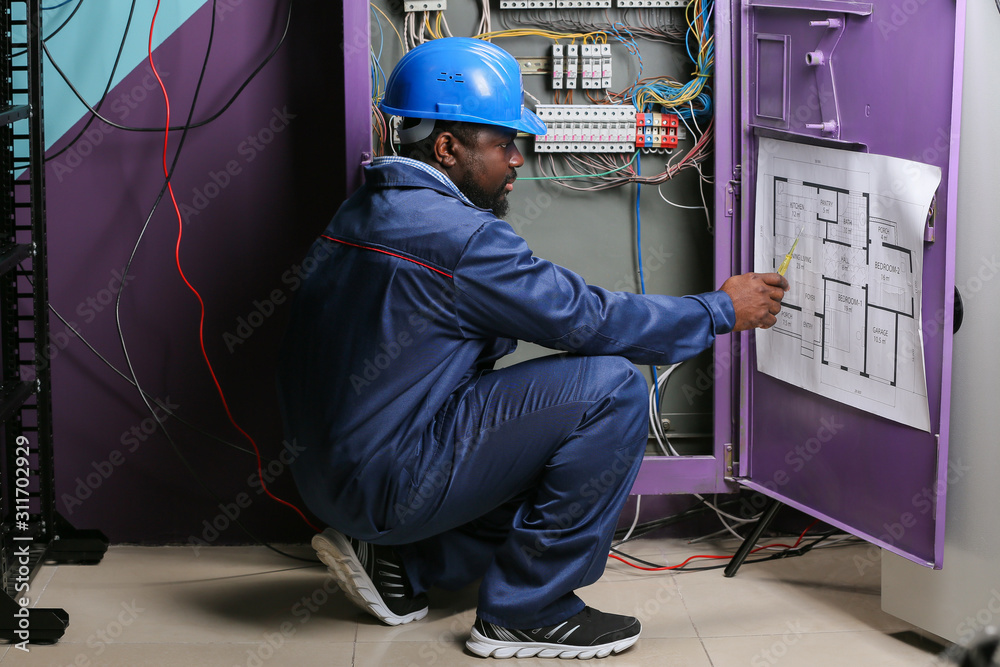 African-American electrician performing wiring in distribution board