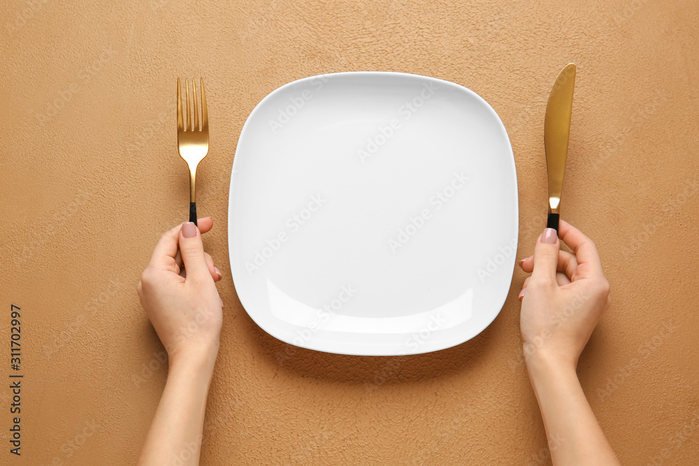 Woman with empty plate and cutlery at table