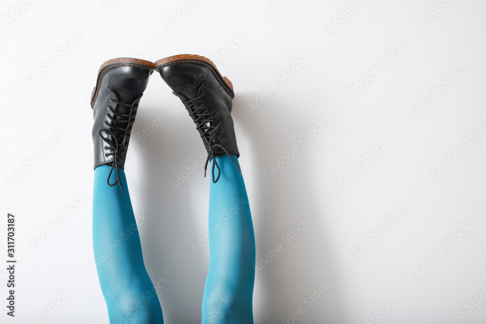 Legs of young woman in stylish shoes against light background