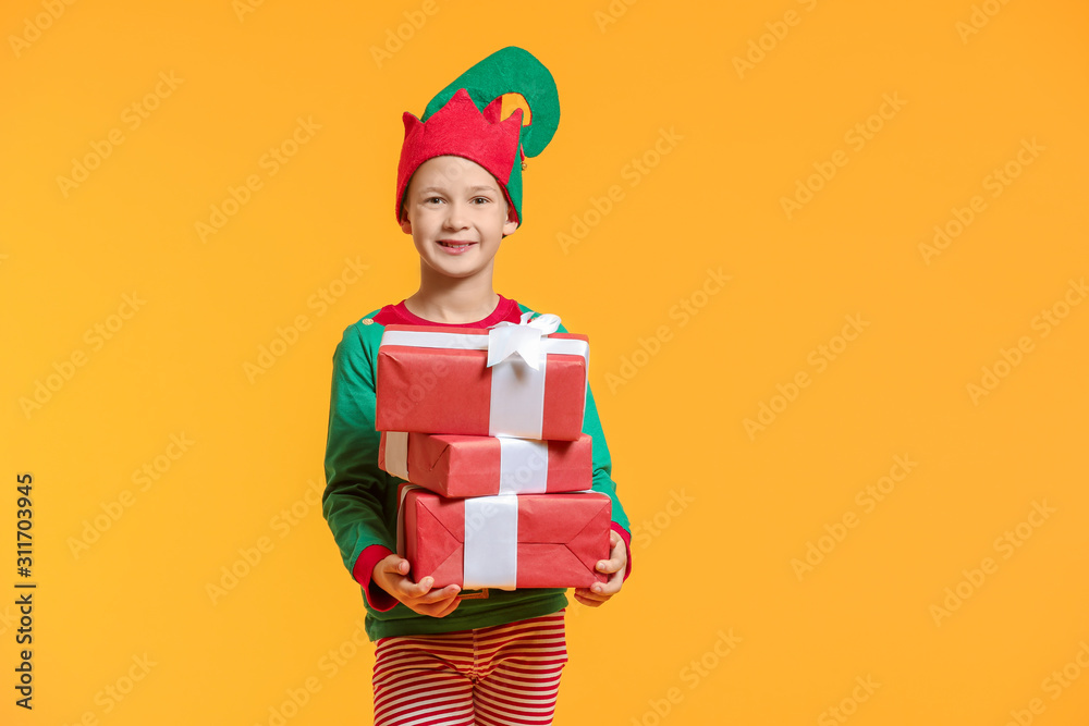 Little boy in costume of elf and with gifts on color background