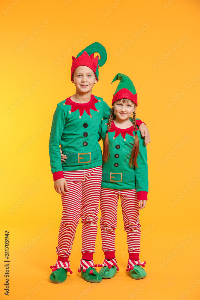 Little children in costume of elf on color background