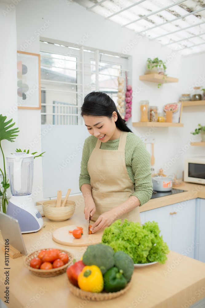 Healthy food, diet concept. Asian woman cooking vegetable salad for dinner, cutting ripe tomatoes on