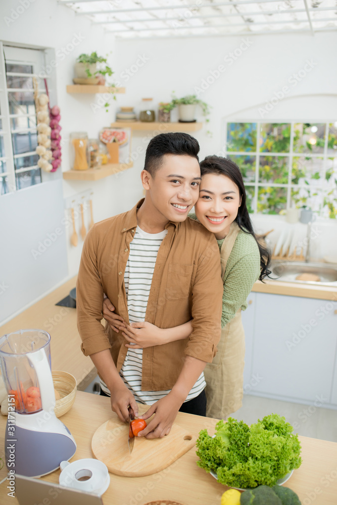 Young Asian couple. Standing cooking in the kitchen.