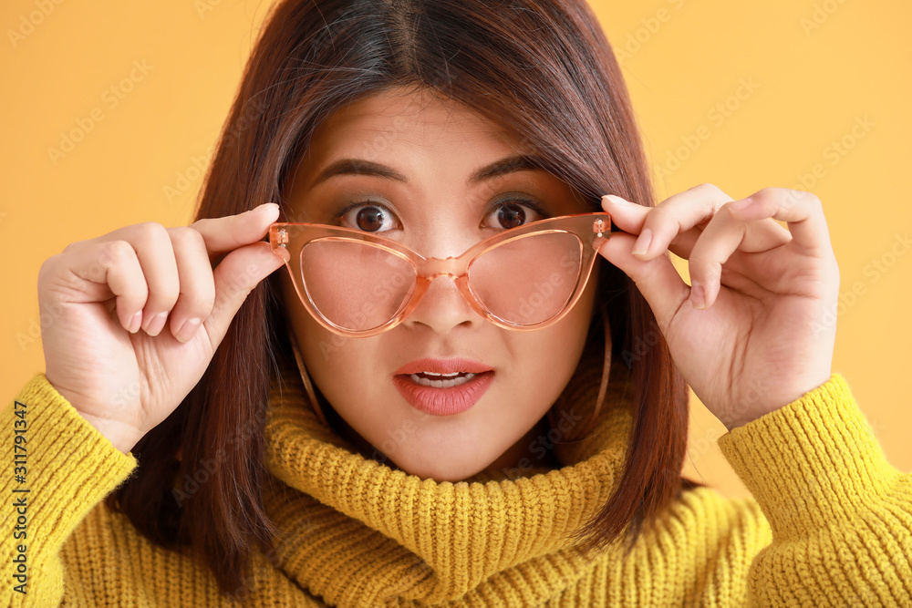 Portrait of surprised young Asian woman on color background