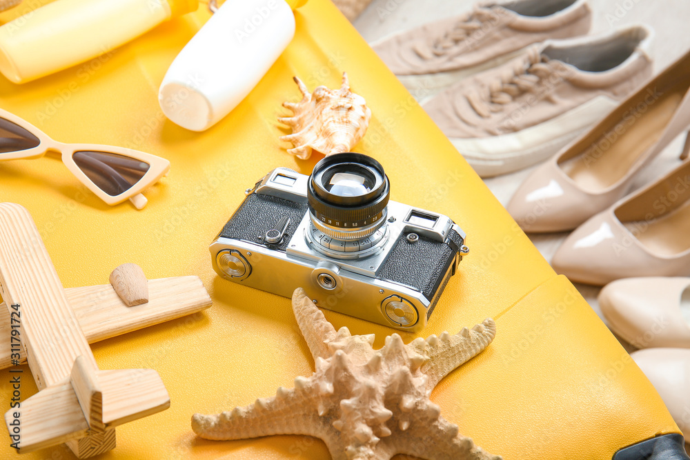 Suitcase and travel accessories with shoes on floor