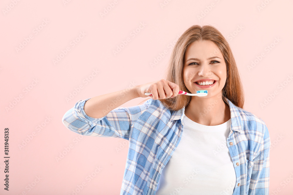 Young woman brushing teeth on color background