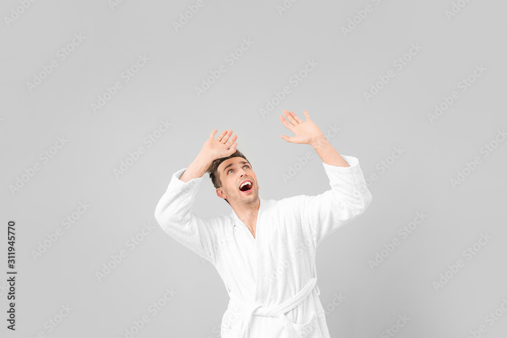 Afraid man in bathrobe on grey background