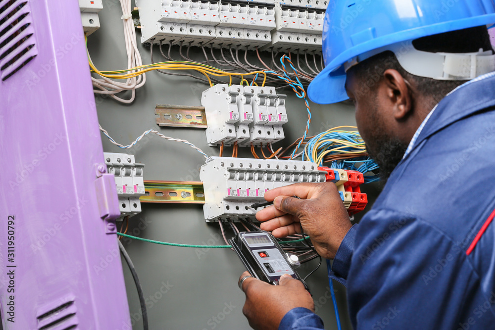 African-American electrician performing wiring in distribution board