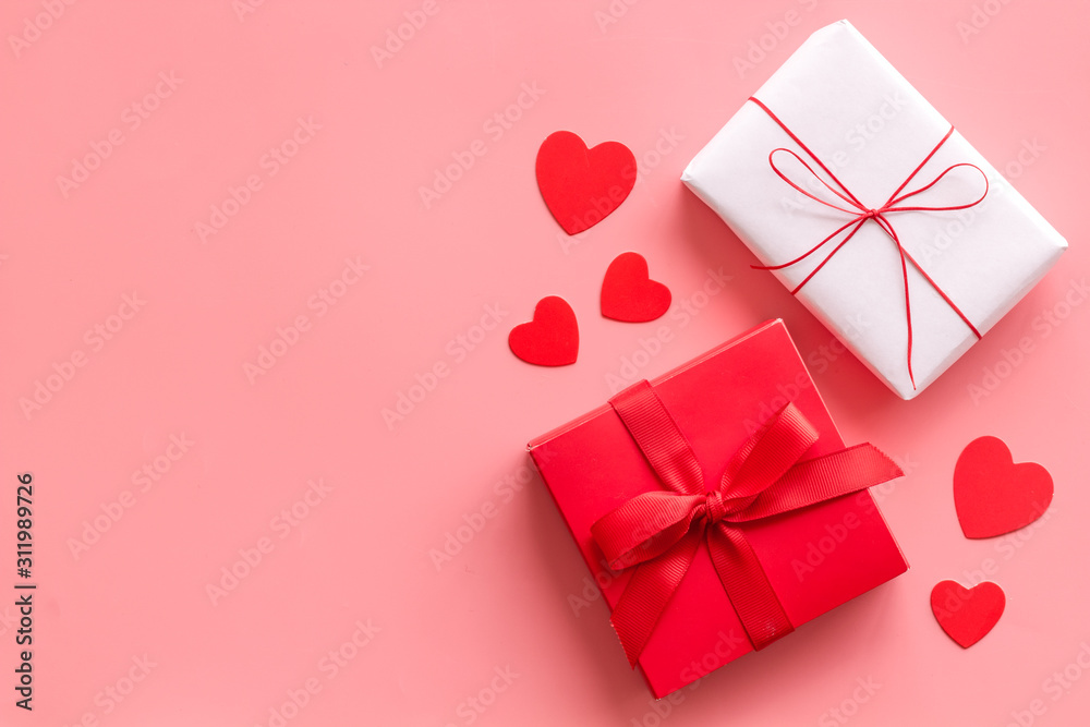 Present to a lover on Valentines Day. Gift boxes near paper hearts on pink background top-down fram