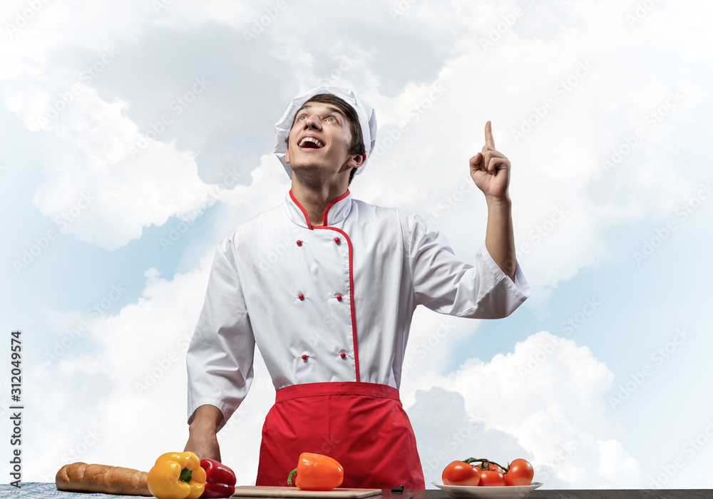 Young male chef standing near cooking table