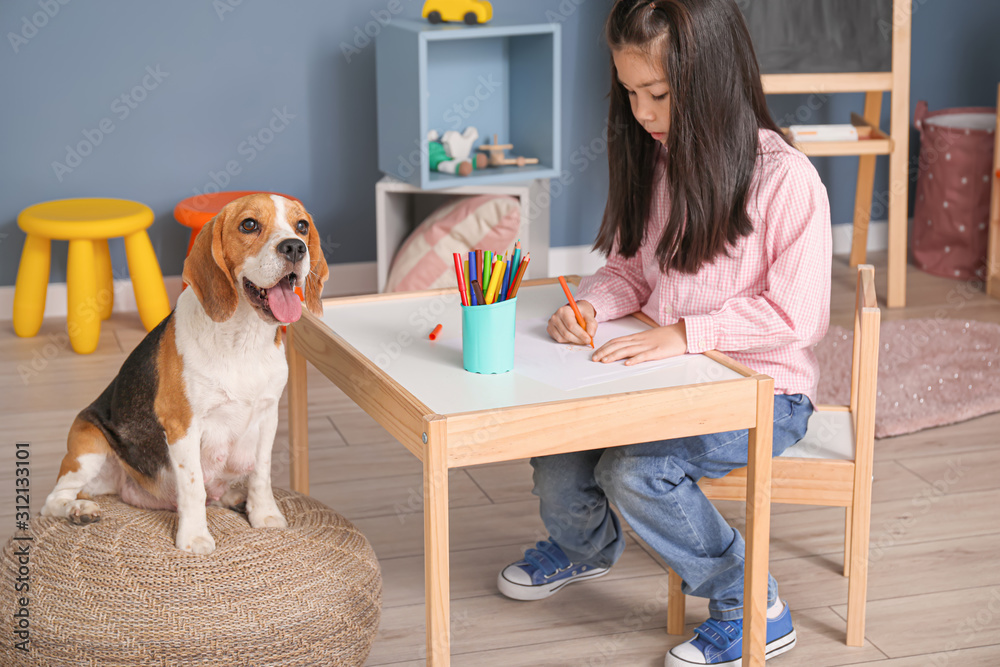 亚洲小女孩和可爱的小猎犬在家画画