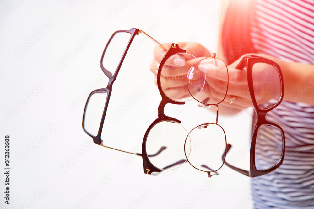 womans hands holding few pairs of glasses isolated on white. Spectacles presentation. Closeup