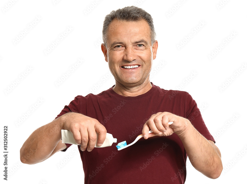 Mature man with toothbrush and paste on white background