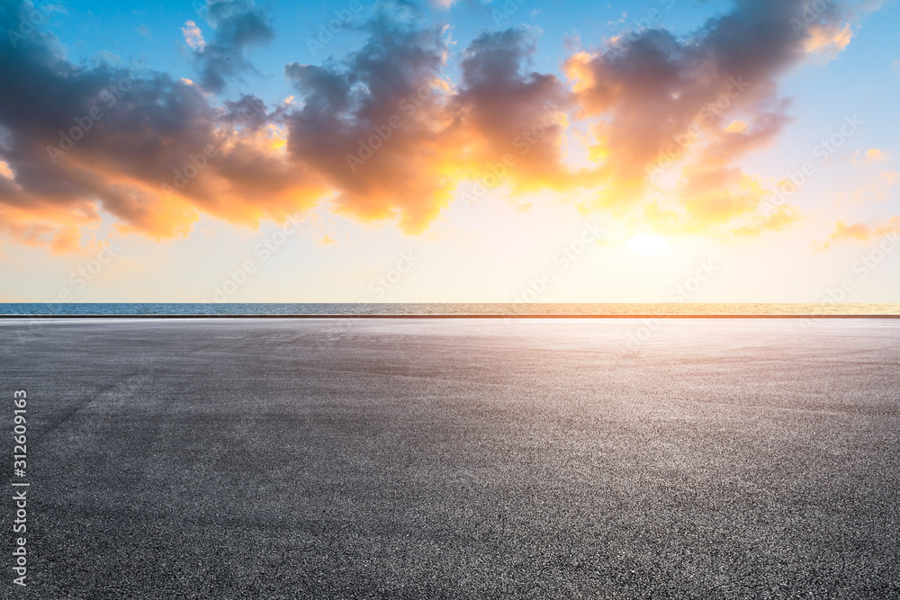 Race track road and lake with colorful clouds at sunset.