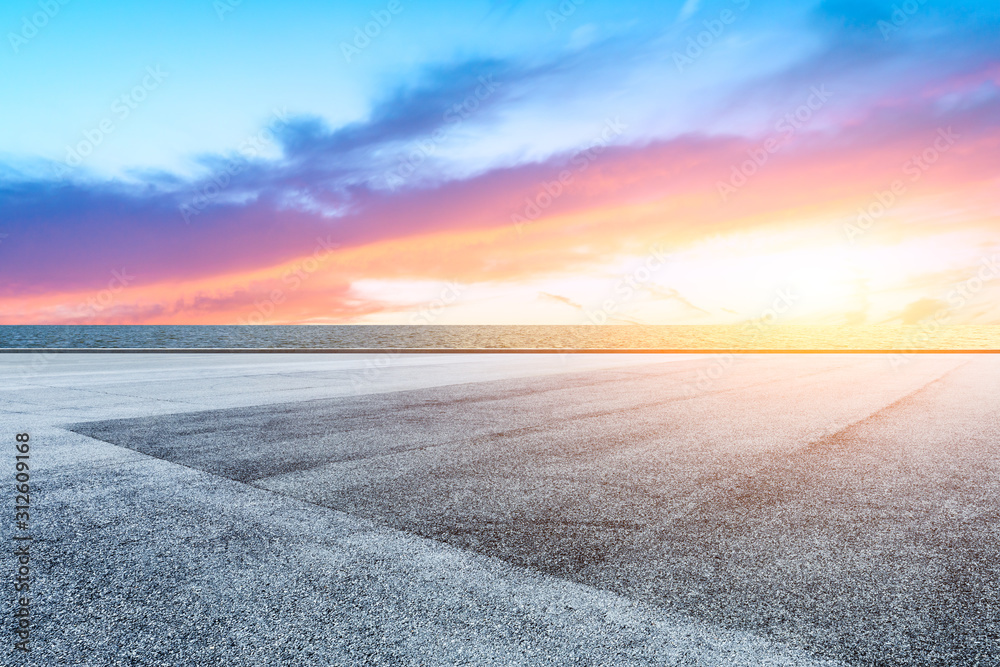 Race track road and lake with colorful clouds at sunset.