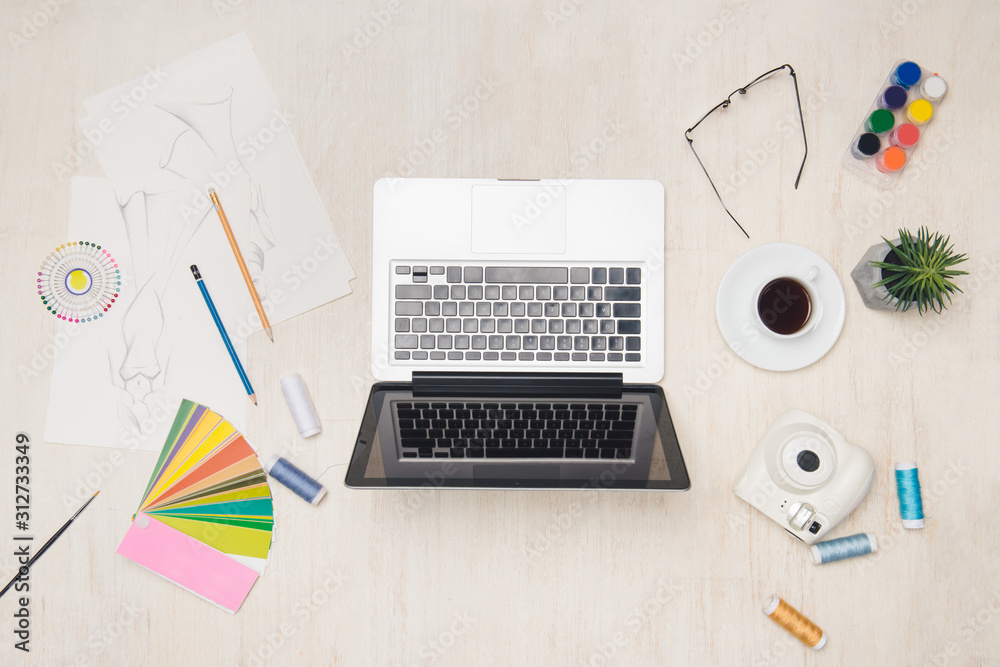 Graphic designer desk essentials top view with wooden texture background.