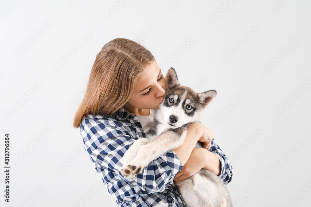 可爱的少女与有趣的哈士奇小狗在浅色背景下