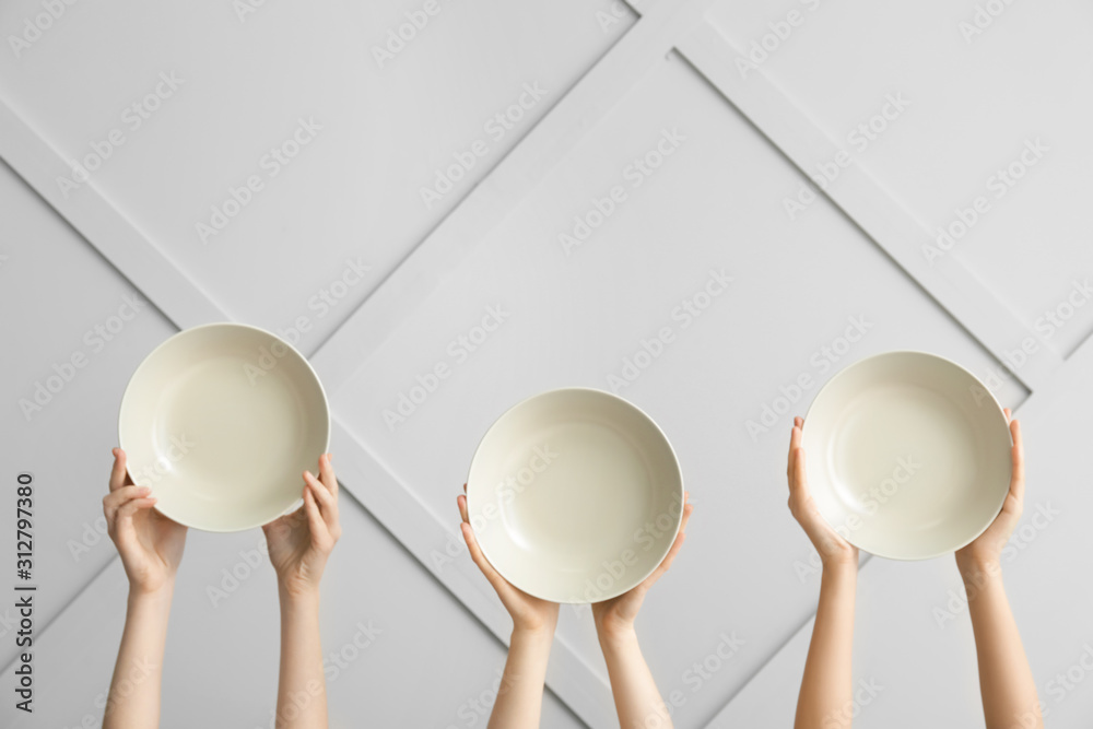 Hands with clean plates on light background