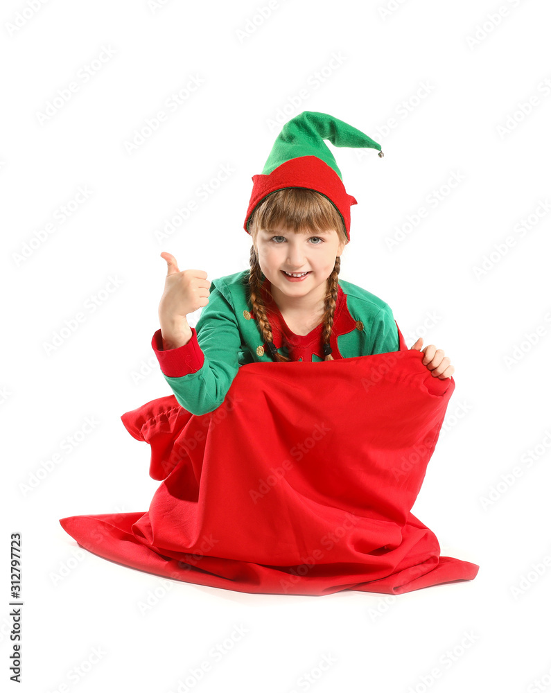 Little elf kid sitting in Santa Claus bag and showing thumb-up gesture on white background