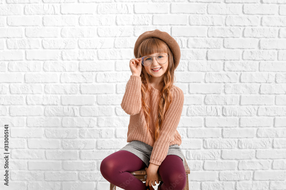 Cute fashionable girl near white brick wall