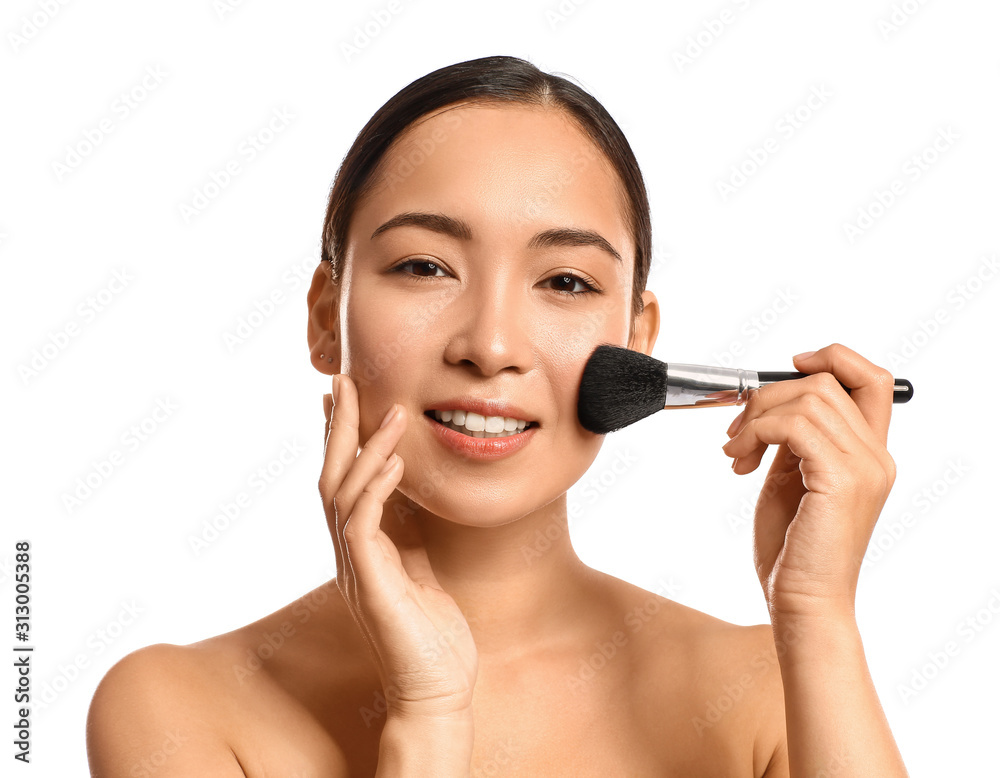 Portrait of young Asian woman with makeup brush on white background